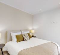 Bedroom in a holiday apartment with light walls, a bed, and lamps on bedside tables.