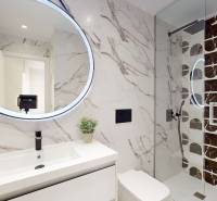 A bathroom in a holiday apartment with a round mirror and a shower corner.
