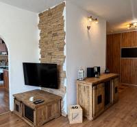 Wooden decor in a 3-room apartment with natural stone and a wall-mounted television.