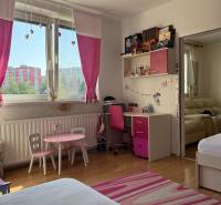 Children's room with pink decor, wooden floor, desk, and sofa.
