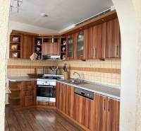 A kitchen in a 3-room apartment with a wooden decor on the floor and built-in appliances.