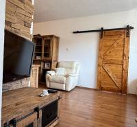 Living room in a three-room apartment with a wood-patterned floor and wooden elements.