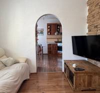 Living room in a three-room apartment with a wooden decor floor and an arched passage.