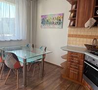 A kitchen in a 3-room apartment with a wooden decor floor and a glass table.