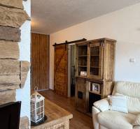 Interior of a 3-room apartment with stone on the wall, a sofa, and furniture with a wooden decor.