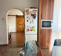 A kitchen in a 3-room apartment with a fridge decor, wooden floor decor, and original chairs.