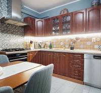 A kitchen in a 3-room apartment with wooden cabinets and a mosaic on the wall.