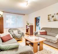 Living room of a three-room apartment with a sofa, armchairs, and a wooden decor floor.
