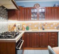 A kitchen with dark wooden cabinets and tiles in a 3-room apartment.