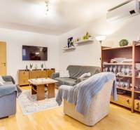 Living room in a 3-room apartment with a wooden decor floor, comfortable sofas, and a television.