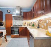 A kitchen in a 3-room apartment with wooden cabinets and a dining table.
