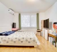 A bedroom in a 3-room apartment with light furniture and a wooden decor floor.