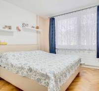 Bedroom with a bed, shelves, and a window in a 3-room apartment, floor with wooden decor.