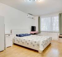 Bedroom in a 3-room apartment with a bed, window, wardrobe, and floor with wooden decor.