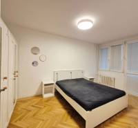 Bedroom in a two-room apartment with wood-patterned flooring and white furniture.