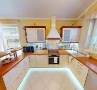 A kitchen in a family house with light cabinets, a table, and modern appliances.