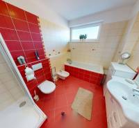 A bathroom in a family house with red and beige tiles, a shower, and a bathtub.