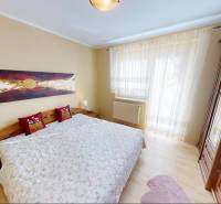 A bedroom in a family house with a wood-patterned floor, a painting, and a large bed.