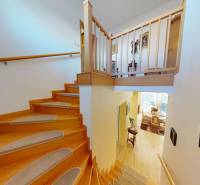 Interior of a family house with a staircase, wooden decor flooring, and railing.