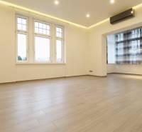 Spacious living area in a 3-room apartment with wood-patterned flooring.