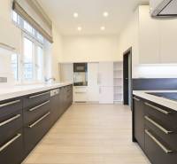 A kitchen in a 3-room apartment with a wooden decor floor and white cabinets.