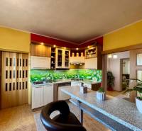 A kitchen in a family house with colorful walls, a bar counter, and decorative cladding.