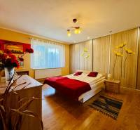 A bedroom in a family house with wooden decor, floral motifs, and red accessories.