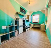 A room in a family house with colorful walls, a shelving wall, and a floor with a wooden decor.