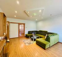 Living room with a large green sofa, a cabinet, and a wooden-patterned floor.