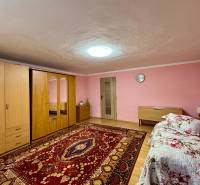 A room in a family house with a wooden decor floor, carpet, and pink walls.