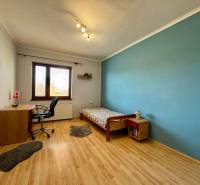 A room with a wooden floor, blue wall, bed, desk, chair.