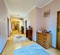 A hallway of a family house with a wooden decor floor and colorful carpets.
