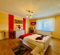 Bedroom in a family house with a bed, dresser, and wooden decor flooring.