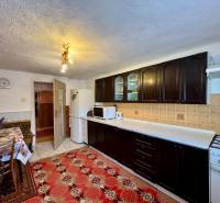 A kitchen in a family house with dark cabinets, carpet, and ceramic tiles.