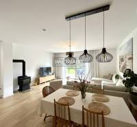 Living room with a fireplace, wood-patterned floor, and dining table in a family house.