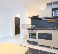 A simple kitchen in a studio apartment with white and black flooring.
