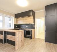 A kitchen in a 3-room apartment with black cabinets and a wooden decor floor.