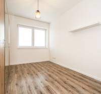 A room in a 3-room apartment with a wooden decor floor, white walls, and a window.