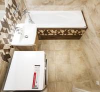 A bathroom in a 3-room apartment with a bathtub, sink, and washing machine, tiled with tiles.