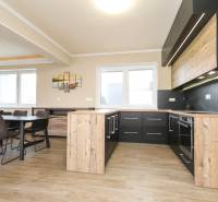 A kitchen with black cabinets and a wood-patterned floor in a 3-room apartment.
