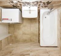 A bathroom in a 3-room apartment with a bathtub, a washing machine, and tiles with a wood texture.