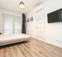 A bedroom with a bed, TV, and a wooden decor floor in a 3-room apartment.
