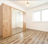 A bright room in a 3-room apartment with a wooden wardrobe and a floor with a wooden decor.