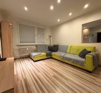 Living room in a 3-room apartment with a corner sofa and a wooden decor floor.