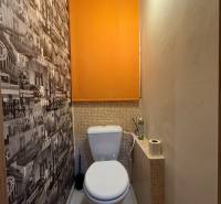 A toilet with graphic wallpaper and orange blinds in a 3-room apartment.