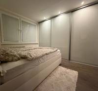 A bedroom in a 3-room apartment with a bed, built-in wardrobe, and floor with a wooden decor.