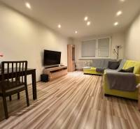 Living room with a sofa, dining table, and wood-patterned flooring in a 3-room apartment.