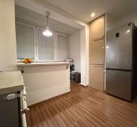 A kitchen in a 3-room apartment with a refrigerator, a cabinet, and a floor with a wooden decor.