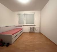 A room in a three-room apartment with a bed, blinds, and a floor with a wood decor.