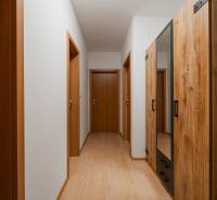 A hallway in a 2-room apartment with a wooden decor floor and wooden doors.